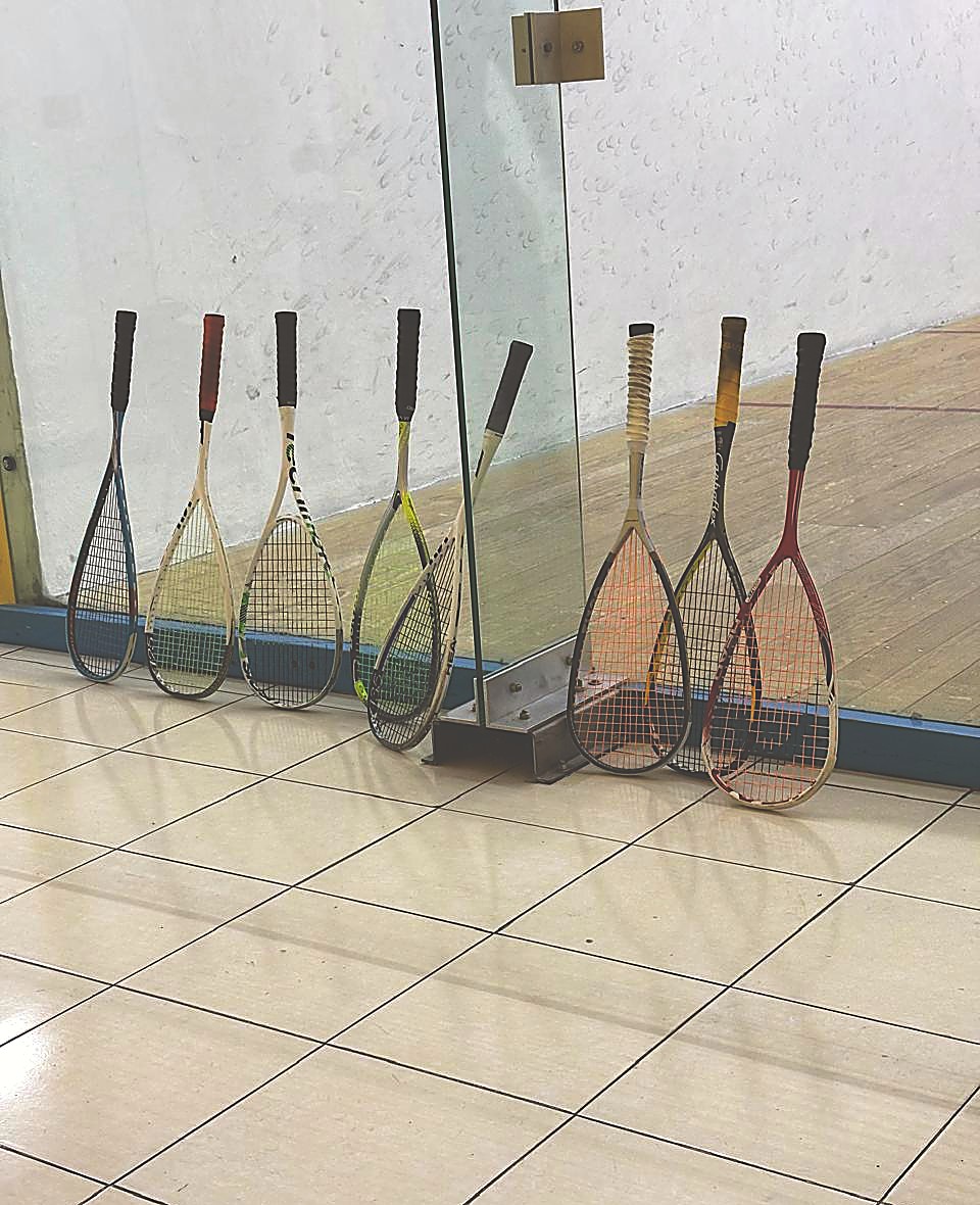 Raquetas de squash recargadas en la pared de vidrio